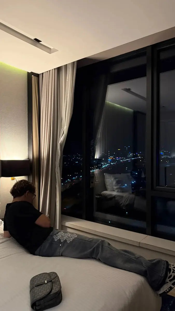 Embroidered reda studio jeans in a room overlooking the city at night