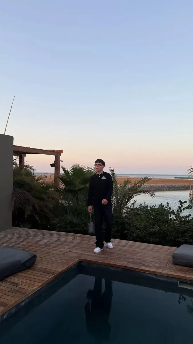 All-black reda studio outfit by a poolside facing the sea at sunset